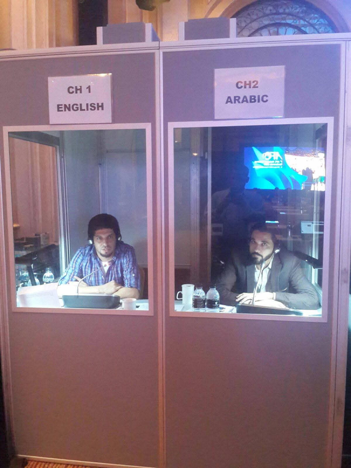 Two interpretation booths labelled English and Arabic at a conference